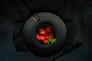 Served summer dessert with watermelon balls and mint in black stoneware on black background