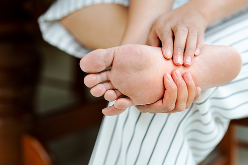 Woman massaging her painful barefoot, healthcare and medical concept