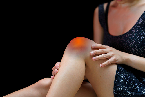 Close up young woman suffering from pain in knee.