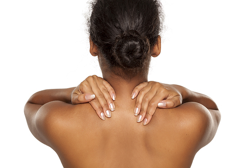 Back view of nude dark-skinned woman touching her neck on a white background