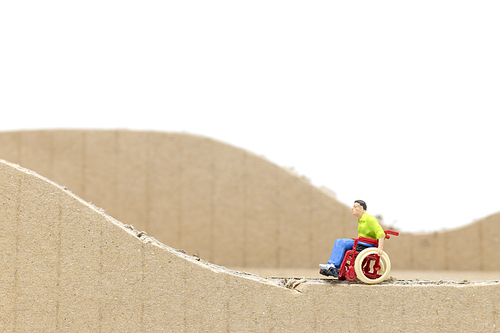 Miniature people Man in wheelchair  isolate on white background