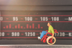 Miniature people : Disabled man sitting in wheelchair Tuning into a radio station