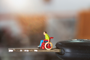 Miniature people : Disabled man sitting in wheelchair  on car key