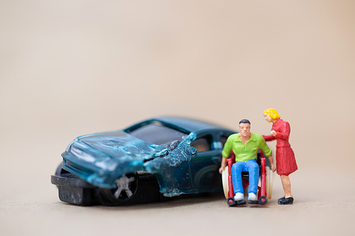 Miniature people : Disabled man sitting in wheelchair  on on wooden background , Accident concept
