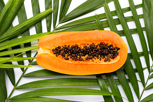Sweet ripe papaya on tropical palm leaves. Top view