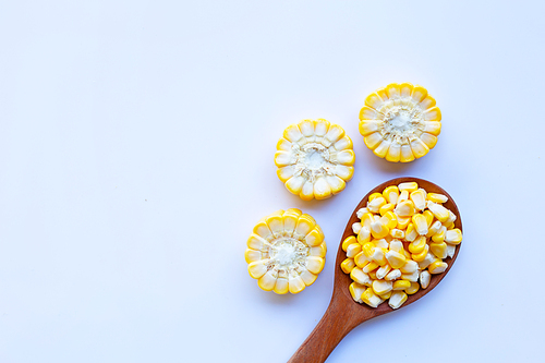Corn seeds on wooden spoon and ripe corn cobs on on white background