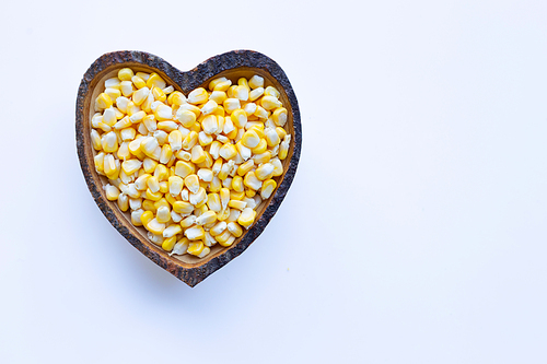 Corn seeds in wooden heart shape dish on white background