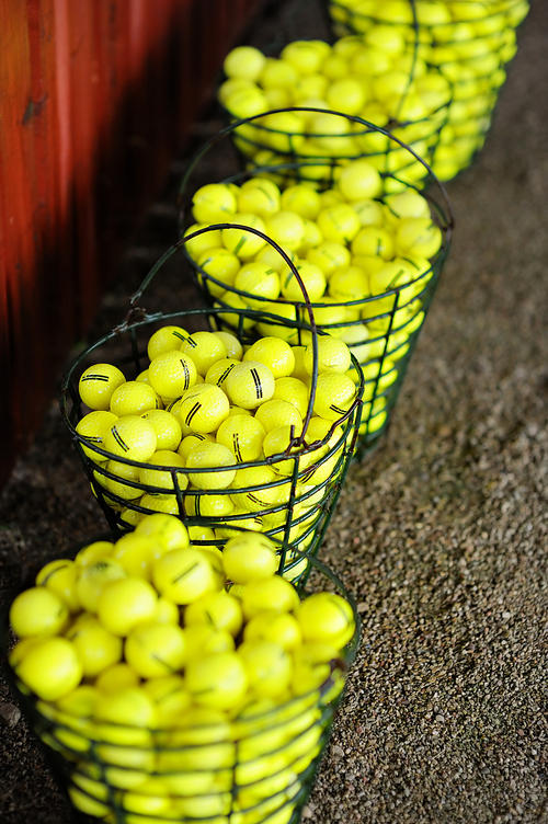 Baskets of yellow golf balls on a golf field