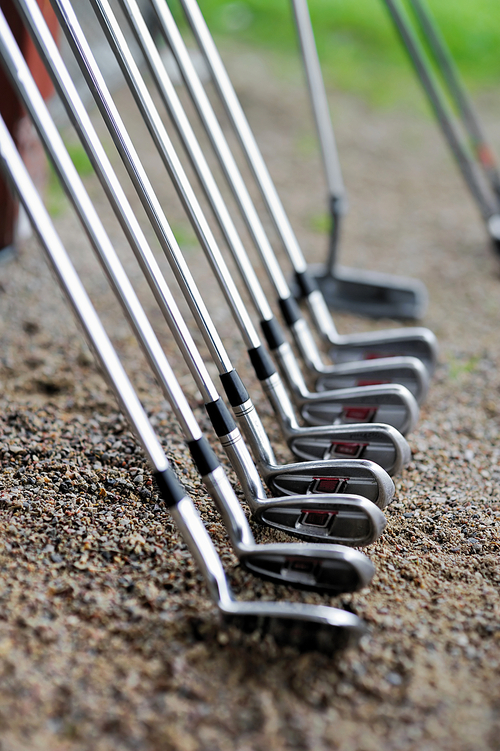 A set of golf clubs in a row