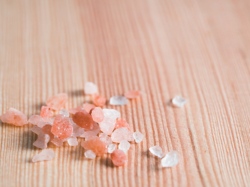 Himalayan pink salt in crystals on wooden background. Copy space