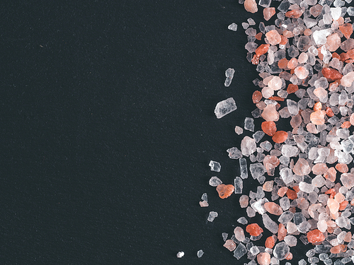 Himalayan pink salt in crystals on black stone background. Copy space