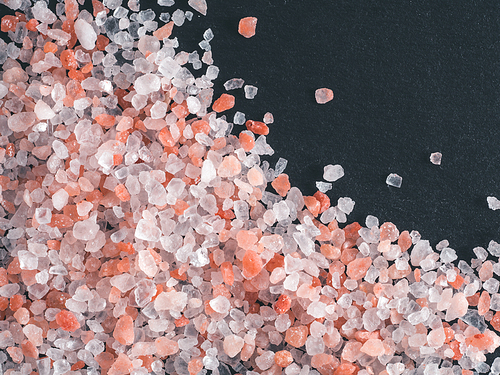 Himalayan pink salt in crystals on black stone background. Copy space