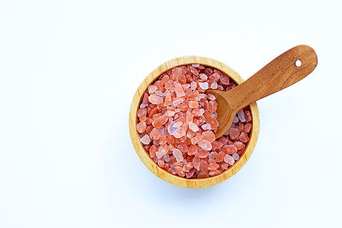 Pink himalayan salt in wooden bowl on white background. Copy space