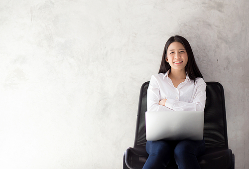 Portrait of asian young woman smile using laptop on chair, business freelance concept.