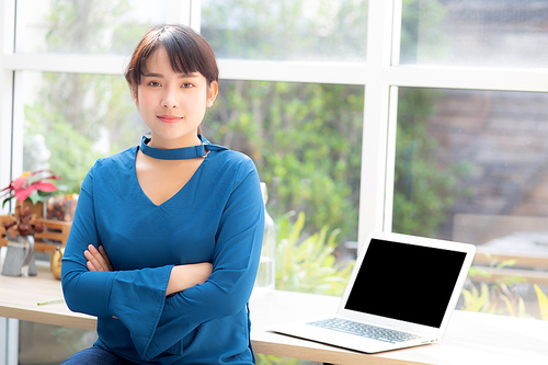 Beautiful of portrait asian young woman sitting looking camera and laptop on table at coffee shop, professional female freelance using notebook computer with connect to internet job.