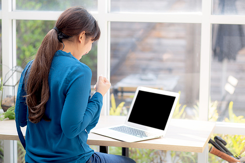 Beautiful portrait asian young freelance woman working online laptop with smile and happy at cafe shop, girl using notebook computer with excited and glad, business and success concept.