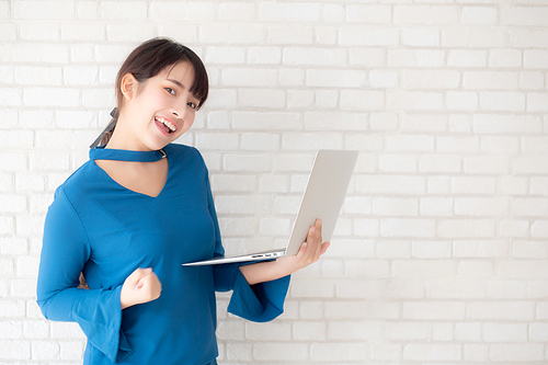 Beautiful freelance young asian woman confident using laptop computer online internet with success, blogger girl expression of excited with achievement from work and having prond in triumph.