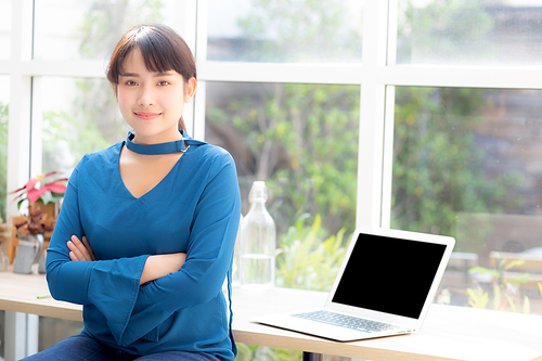 Beautiful of portrait asian young woman sitting looking camera and laptop on desk at coffee shop, professional female freelance working notebook computer connect internet online job, business concept.
