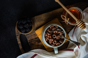 Traditional breakfast with chocolate cornflakes, yogurt and honey on rustic background