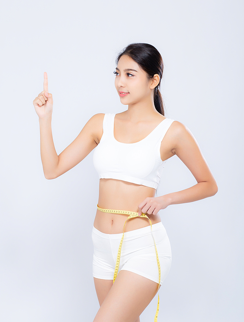 Beautiful portrait asian woman diet and slim with measuring waist for weight finger pointing something isolated on white, girl have cellulite loss with tape measure, health and wellness concept.