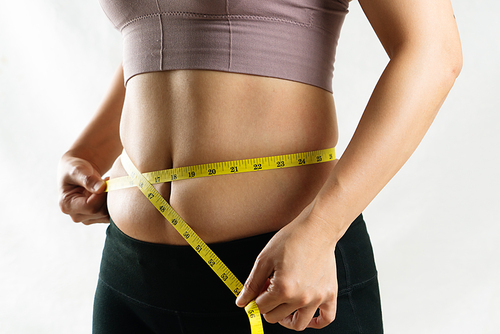 young woman measuring her excessive belly fat waist with measure tape, woman diet lifestyle concept