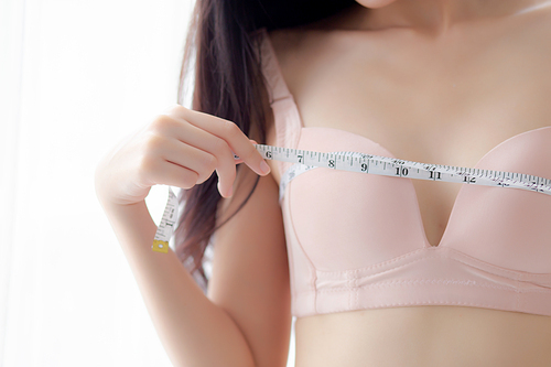 closeup beautiful young asian woman  body slim measuring breast for control weight loss in the room, beauty asia girl figure thin measure size of bust for diet, health and wellness concept.