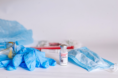 Coronavirus vaccine. Medical preparation in ampoule. Treatment for the disease, covid-19. The vaccine on a white background and on the background of a syringe, rubber gloves and goggles.