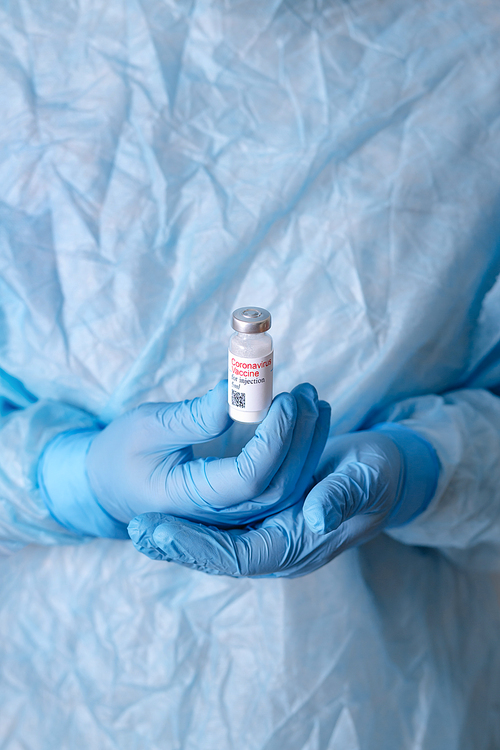 Coronavirus vaccine. Doctor with a vaccine. Nurse holding a coronavirus vaccine. Hands holding a coronavirus vaccine ampoule, against Covid-19.