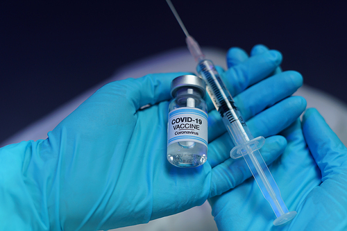 Hand in blue glove holding vaccine and syringe injection for prevention, immunization and treatment from corona virus infection.