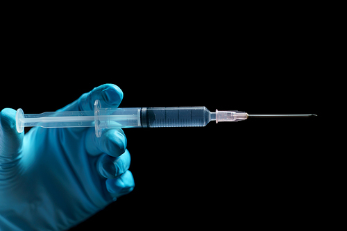 Doctor's hands holding syringe closeup on black background.