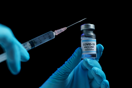 Hand in blue glove holding vaccine and syringe injection for prevention, immunization and treatment from corona virus infection.