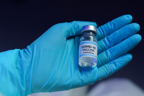 Hand in blue glove holding vaccine and syringe injection for prevention, immunization and treatment from corona virus infection.