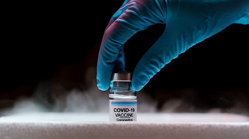 Doctor's hand holding bottle vaccine Covid-19 from storage box. Medication treatment concept.