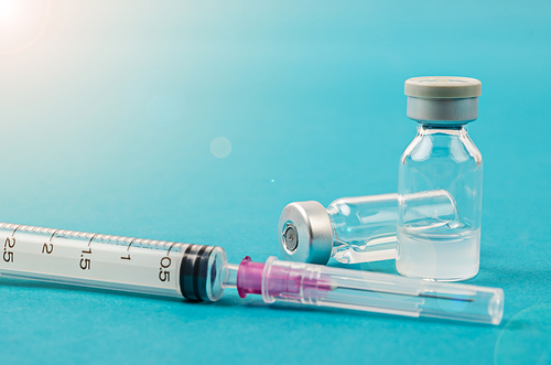 Vaccine vial dose with needle syringe, medical concept vaccination in laboratory background.