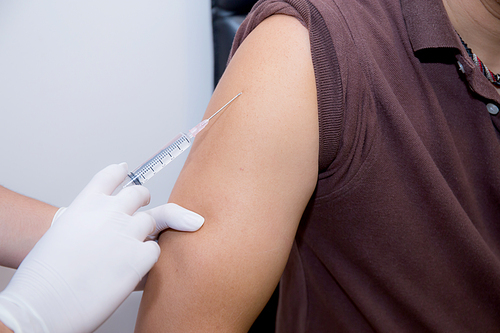 Close-up Of Doctor Injecting Patient With Syringe To Collect Blood