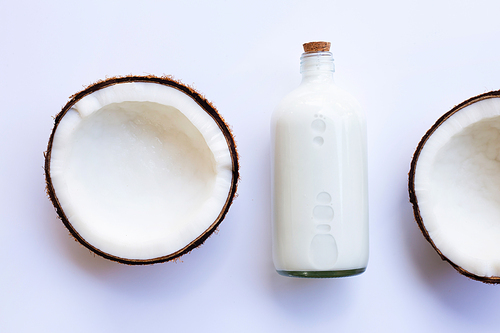 Half Coconut with bottle of coconut milk on white background.