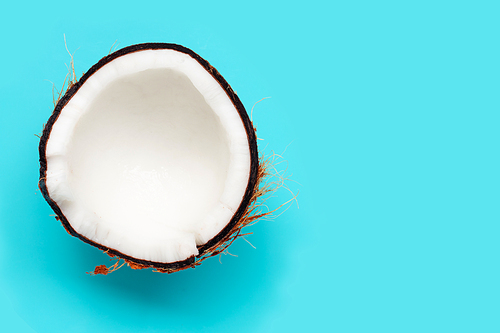 Half coconut on blue background. Copy space