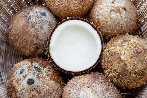 Top view of ripe coconuts in wicker basket.