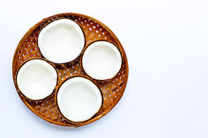 Half coconuts on wooden bamboo threshing basket on white background. Copy space