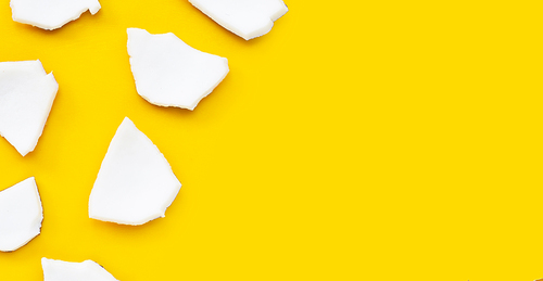 Coconut cut pieces on yellow background. Top view