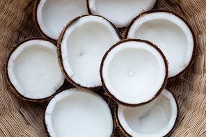 Top view of ripe coconuts in wicker basket.