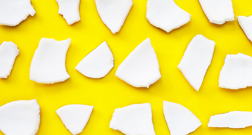 Coconut cut pieces on yellow background. Top view