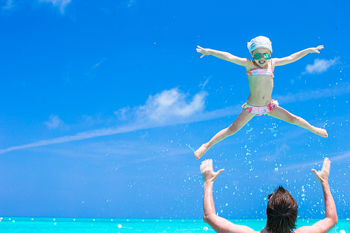 Happy father play with little adorable daughter in perfect sea