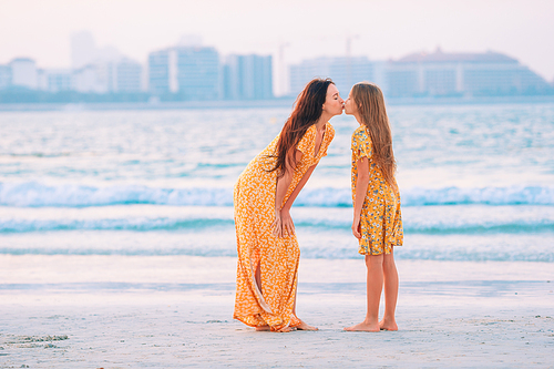 Young beautiful mother and her daughter on the beach at sunset