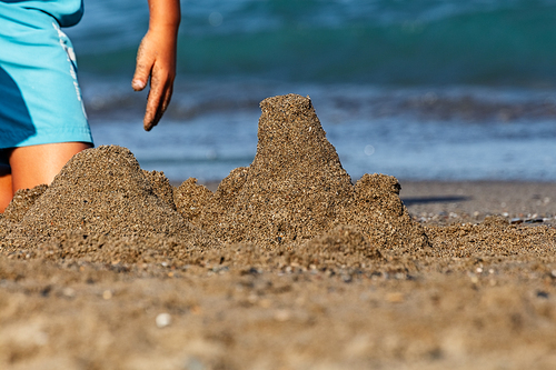 Boy making castles in the sand of the shore of the beach. Summer at the beach