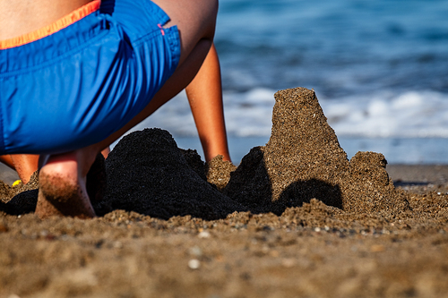 Boy making castles in the sand of the shore of the beach. Summer at the beach
