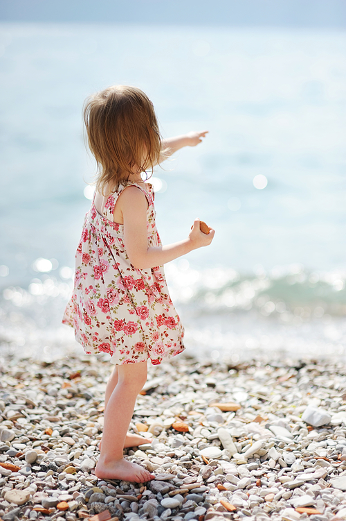 Little girl having fun on a pebble beach