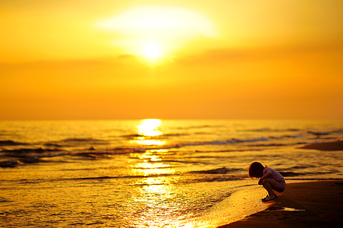 Little child having fun on a sunset beach