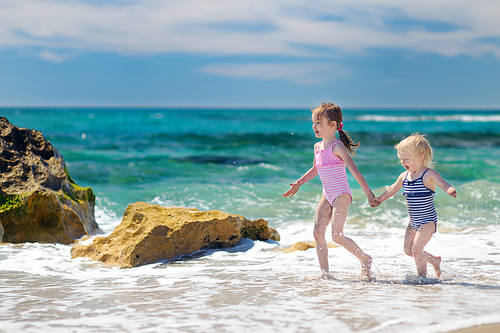 Two little sisters having fun on a sandy beach