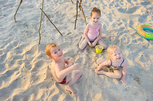 Three little kids having fun on a sandy beach